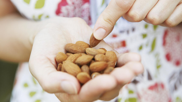 Close Up Of Woman Eating handful Of Almonds
